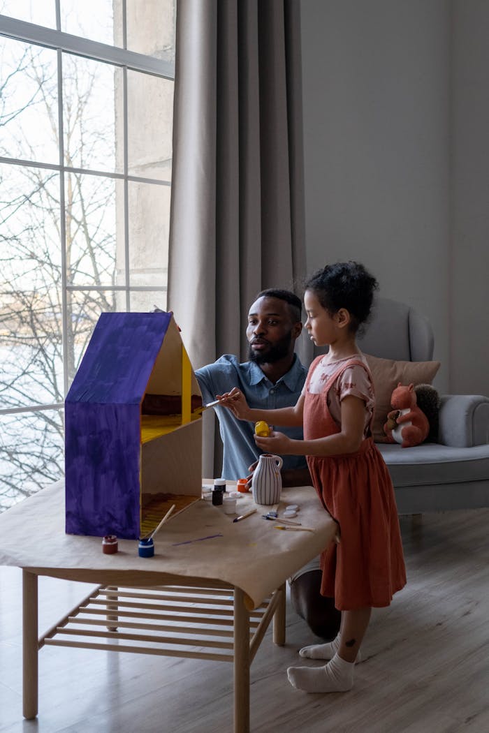 Mastering the First Impression: Your intriguing post title goes here A father and daughter enjoy painting a dollhouse indoors, spending quality family time together.